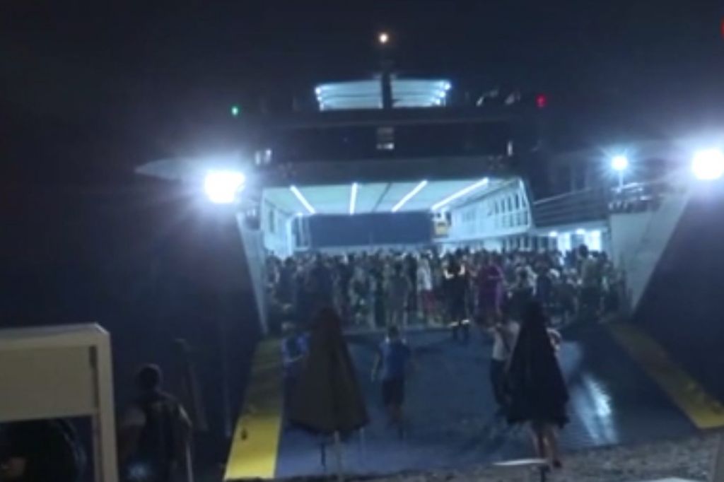 Άνθρωποι επιβιβάζονται στα πλοία, ενώ τα πάντα καίγονται