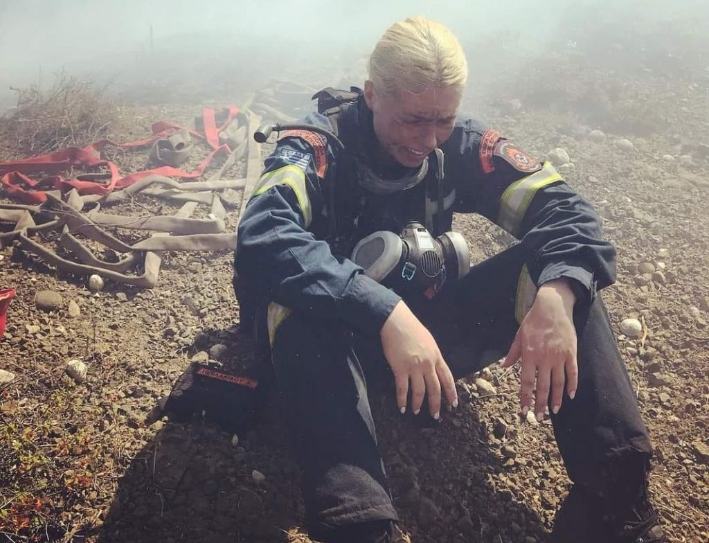 Γυναίκα πυροσβέστης ξαποσταίνει μέσα στους καπνούς από τις φωτιές